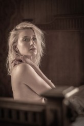 piotrwisinski Nikolina – młoda, piękna i niezwykle subtelna kobieta – została uchwycona w intymnej chwili spokoju. Siedząc naga na łóżku, emanuje naturalnością i delikatnością. Jej ciało układa się swobodnie, bez napięcia, a kompozycja podkreśl