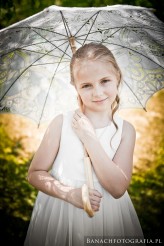 banach Piękny, słoneczny dzień i sympatyczna dziewczynka ukryta przed ostrym słońcem pod stylowym parasolem.
